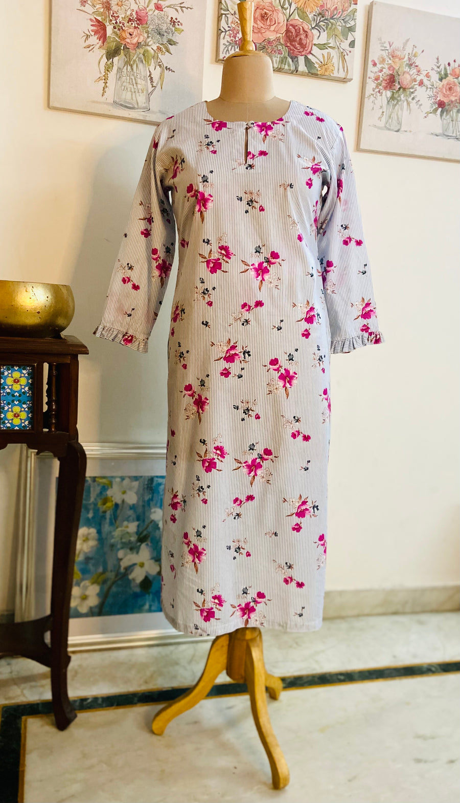 Done on the softest of cottons -This lovely intricate print has light blue grey stripes and on it the most beautiful hibiscuses in deep pink all over. It has a delicate gather at the end of each sleeve and a tiny button detailing on the neckline. From Mulmul And More by Priyanka Bhambry 